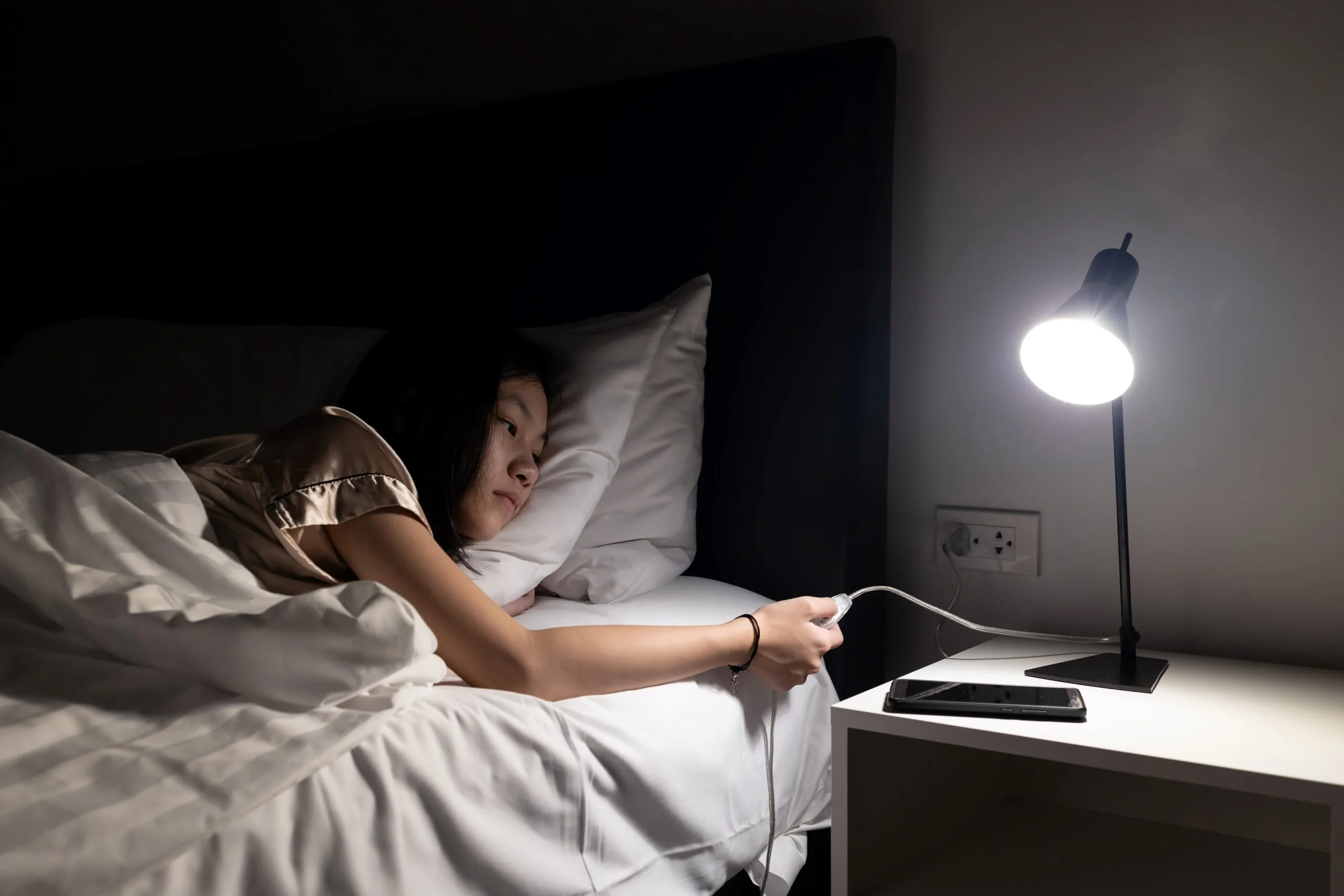 Child in bed turning off lamp