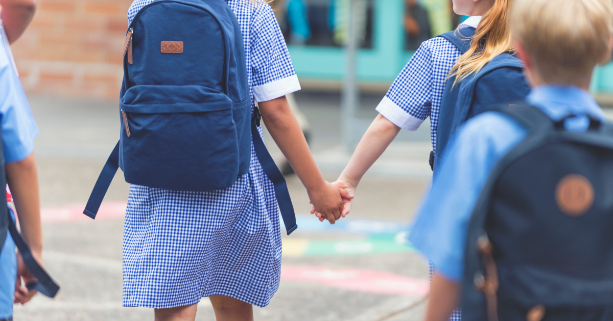Children walking across the playground hand-in-hand.